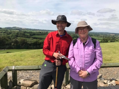 Two people standing next to each other in front of hills